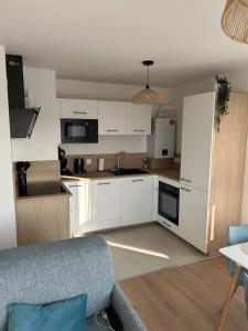 a kitchen with white cabinets and a blue couch at Le spot in Camiers +8 photos