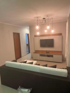 a living room with a couch and a flat screen tv at Summer Suites Casa Arraial do Cabo in Arraial do Cabo