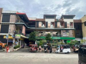 a building on a city street with people and vehicles at Rielena Plaza Hotel and Suites in Molave