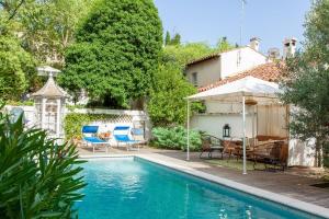 a swimming pool with chairs and a house at Maison Blanche in Nîmes