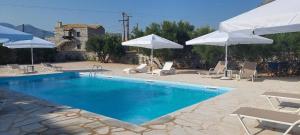 a swimming pool with white umbrellas and chairs at Areopoli Home 17 in Areopoli