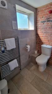 a bathroom with a toilet and a brick wall at The Old Bakery in Lincoln +14 photos