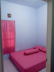 a pink bed in a room with a red curtain at Soraya Homestay 2 in Tulungagung
