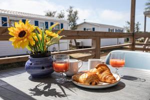 un tavolo con un piatto di croissant e un vaso con un fiore di Camping Barberousse a Gruissan Altre 11 foto