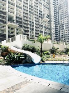 a swimming pool with a slide in front of some buildings at JFam Suites Allegra Condo with Balcony, FREE Parking in Manila