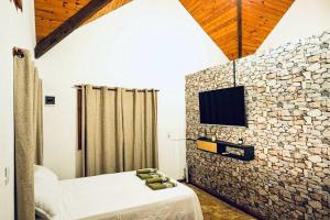a bedroom with a stone wall with a bed and a tv at Cabaña Amare in Puerto Bossetti