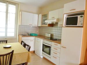 Una cocina con gabinetes blancos y una mesa y un microondas. en Villa Lutetia, en Le Mont-Dore
