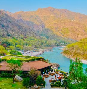 einen Fluss mit einem Restaurant neben einem Berg in der Unterkunft ALOHA ON SACRED GANGES with INFINITY POOL in Rishikesh