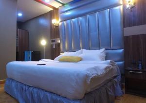 a bedroom with a large bed with a blue headboard at Grand Diamond Hotels & Suites LTD in Owerri