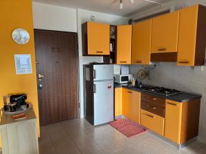a kitchen with yellow cabinets and a white refrigerator at Terrazza Nutshell Parco, Centro, Policlinico in Monza