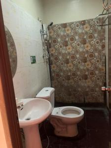 a bathroom with a toilet and a sink at Rielena Plaza Hotel and Suites in Molave