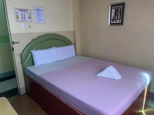 a small room with a bed with a green headboard at Rielena Plaza Hotel and Suites in Molave +10 photos