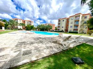 プンタ・カナにあるClose to the Airport Serena Pools BQQのラウンジチェア2脚付きのスイミングプール、建物