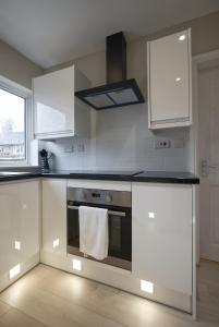 a kitchen with white cabinets and an oven with a towel at Luxury Harborne Home, Perfect for Contractors & Families 5 Mins from QE & Uni in Birmingham