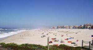 a beach with a bunch of people on the sand at Parque de Campismo da Praia de Pedrogao in Coimbrão