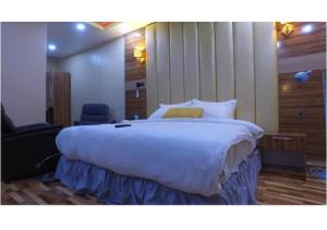 a bedroom with a large white bed with a yellow pillow at Grand Diamond Hotels & Suites LTD in Owerri