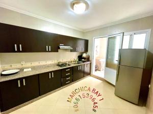 a kitchen with black cabinets and a stainless steel refrigerator at Marchica Bay 1 holiday Apartment in Nador