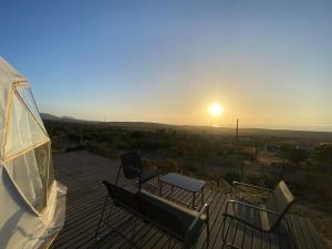 a couple of chairs sitting on a deck with the sunset at Vilos Domo excepcional domo privado in Los Vilos