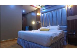 a bedroom with a large white bed with a blue headboard at Grand Diamond Hotels & Suites LTD in Owerri