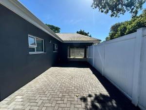 a brick driveway leading to a house with a white fence at Prospect Cottage B in Gqeberha