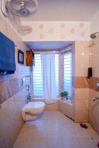 a bathroom with a toilet and a tub and a window at Woodburry Mansion, Cozy Nainital Homestay in Nainital