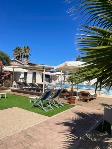 a resort with chairs and umbrellas next to the ocean at Le Palme Holidays in Palmadula