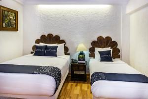 two beds in a hotel room with two bedsitures at Capital O Hotel Central, Xalapa in Xalapa