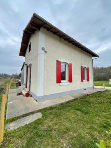 ein kleines Haus mit roten Fensterläden und einem Garten in der Unterkunft La petite maison in Sainte-Marie-de-Chignac