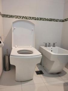 a white bathroom with a toilet and a sink at Los Naranjos in San Salvador de Jujuy +18 photos