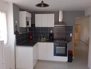 a kitchen with white cabinets and a stove top oven at "Les Tournesols" in Saint-Martin-dʼArdèche