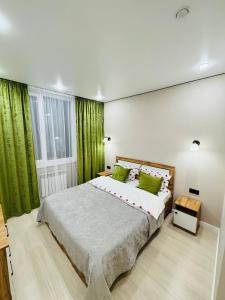 a bedroom with a large bed with green curtains at Syganak Apartments in Astana