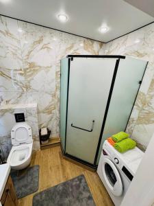 a bathroom with a toilet and a glass door at Syganak Apartments in Astana