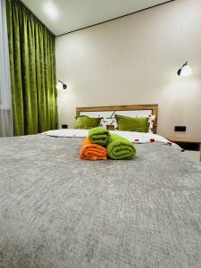 a bedroom with a large bed with green curtains at Syganak Apartments in Astana
