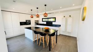 eine Küche mit weißen Schränken und einem Tisch mit Obst darauf in der Unterkunft Luxueuse Villa contemporaine avec piscine à deux pas des plages de Biarritz in Bidart