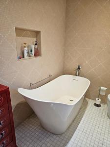 a white tub in a bathroom with a tiled floor at Brentford house in Brentford