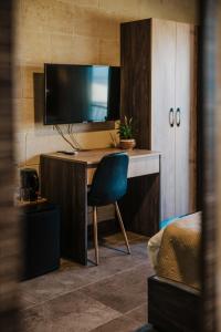 a room with a desk with a television and a chair at 49 Sunrise Lodge in Għajnsielem