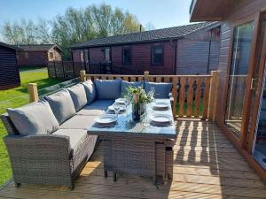 a patio with a couch and a table on a deck at Lakeland Lodge- 3Bed-2 Bath- Private Patio in Carnforth