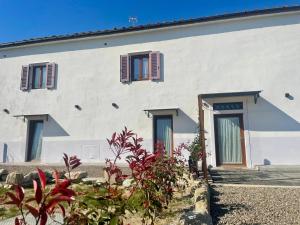 a white house with red shuttered windows and plants at Castrum Gallani in Barberino di Mugello