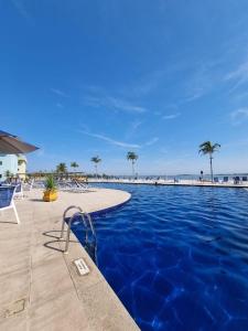 a swimming pool with the beach in the background at Golden Lake Experiência Inesquecível 6 apto 301 in Arraial do Cabo