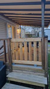 Un porche de madera con barandilla de madera en una casa. en Mobihome les sables du midi, en Valras-Plage