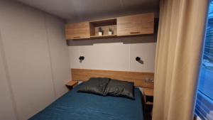 Un pequeño dormitorio con una cama azul y una ventana en Mobihome les sables du midi, en Valras-Plage 2 fotos más