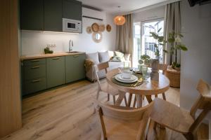 a kitchen and living room with a table and chairs at Apartamenty Wyspa Jastarnia Oliwkowy in Jastarnia