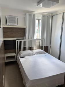 a bedroom with a white bed and a microwave at Flat 02 quartos em Boa Viagem, 2 min a pé da praia in Recife
