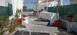 a patio with two chairs and tables and potted plants at B&B CASAVACANZE CHIESA MADRE in Carovigno