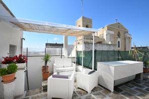 a balcony with white chairs and a table and a church at B&B CASAVACANZE CHIESA MADRE in Carovigno