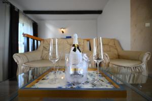 a bottle of wine sitting on a table with two glasses at Pensiunea Mama Lia in Haţeg