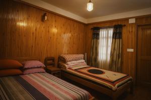 two beds in a room with wood paneling at Miryok Homes in Mirik