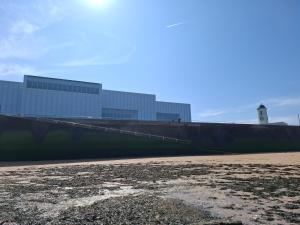 a wall with a building in the background with a beach at Westbrook Lodge Guest House in Margate