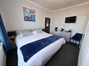 a bedroom with a large bed with a blue blanket at Westbrook Lodge Guest House in Margate