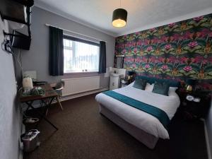 a bedroom with a large bed and a floral wall at Westbrook Lodge Guest House in Margate